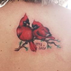 the back of a woman's neck with two red birds on it, one is kissing