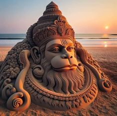 a sand sculpture of a man's head and beard on the beach at sunset