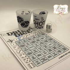 two shot glasses with dices next to them on top of a board game that says it's time to shoot down