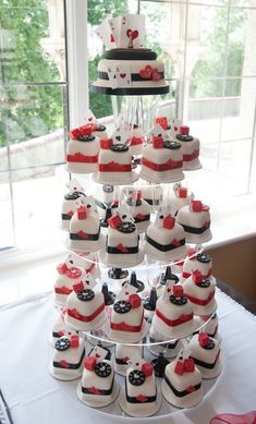 a wedding cake and cupcakes are arranged on a table in front of a window