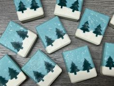 twelve blue and white christmas tree shaped cookies on a wooden table with frosted icing