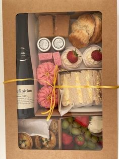 a box filled with different types of pastries and desserts next to a bottle of wine