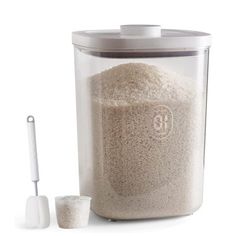 a large container filled with rice next to a measuring cup and utensil on a white background