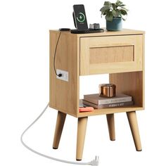 an electronic device is plugged in to a wooden bedside table with two books and a plant on top