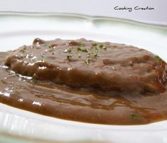 a white plate topped with meat covered in gravy