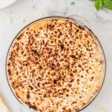 a pie sitting on top of a white counter next to a knife and bowl filled with food