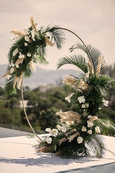 a wedding arch decorated with white flowers and greenery on the top of a building