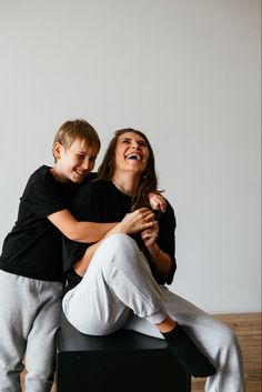 two people sitting on top of each other and smiling at the camera, one person is holding his arm around the woman's shoulder