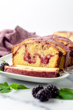 a loaf of raspberry pound cake on a white plate with fresh blackberries