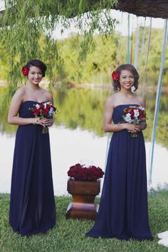 two bridesmaids standing in front of a lake with flowers on their heads and holding bouquets