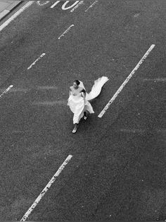 a woman in a white dress is walking down the street