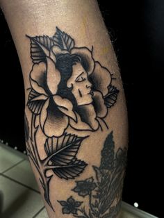 a black and white photo of a woman's leg with flowers on it,