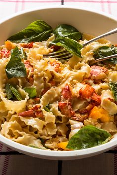 a bowl filled with pasta and spinach on top of a checkered table cloth