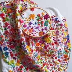 a white shirt with colorful flowers on it and a cross - stitch project in the middle