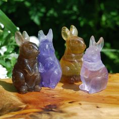 three glass rabbits sitting on top of a wooden table