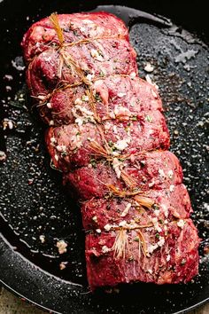 steak in a cast iron skillet with herbs and seasoning on top, ready to be cooked