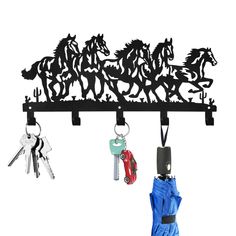 three keys hang from a metal key rack with horses on it and two umbrellas in the foreground