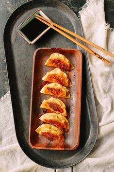 some food is sitting on a tray with chopsticks next to it and sauce