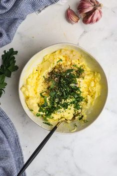 a bowl filled with mashed potatoes and parsley on top of a marble counter