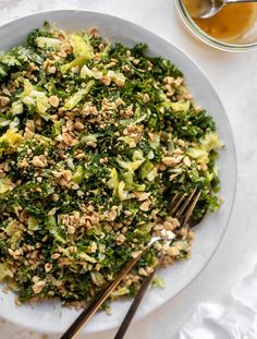 a white plate topped with broccoli salad next to two chopsticks on a table