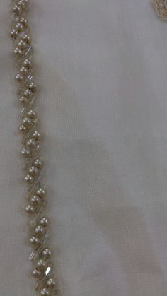 a necklace with pearls on it sitting on top of a white cloth covered tablecloth