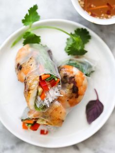 a plate with shrimp wrapped in rice and garnished with cilantro leaves