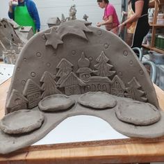 some people are working with clay and making something out of it's shape on a table