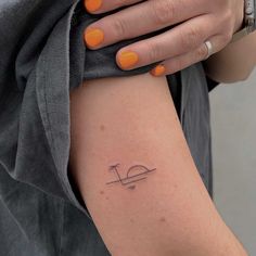 a woman's arm with an orange manicure and a small tattoo on it