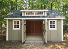 a small shed in the woods with its door open and windows on it's side