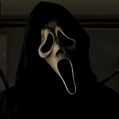 a person wearing a scary mask with its mouth wide open and tongue out in the dark