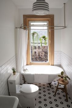 a white bath tub sitting under a window next to a toilet