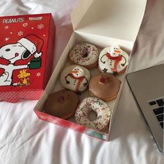 a box of doughnuts sitting on top of a bed next to a laptop