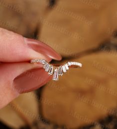 a woman's hand holding a ring with three small diamonds on the middle of it