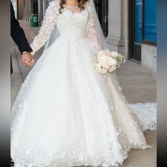 a bride and groom walking down the street holding hands