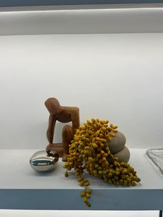 a small wooden figure sitting on top of a table next to some rocks and plants