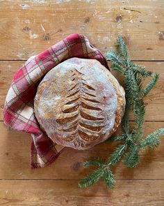 a loaf of bread sitting on top of a wooden table next to a green plant