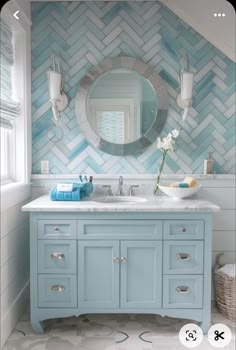 a bathroom with blue and white tiles on the wall, sink and mirror in it