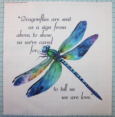 a blue dragonfly sitting on top of a piece of paper with a quote below it