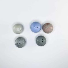 four different colored balls sitting on top of a white surface with holes in the middle