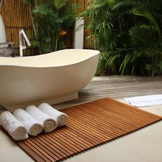 a white bath tub sitting on top of a wooden floor next to a pile of towels