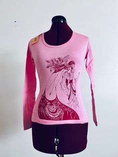 Deadstock 70s pullover t-shirt with Audrey Beardsley screen print art in pink. It has a scooped neckline, a straight hem and art on the front and back.   Material: Cotton Brand: Chandra  Origin: India Color/print: Pink Era: 70's  Size:  Tag says Large,  could fit M-L Approximate Measurements  Bust: 34"-40" Waist: 30"-36" Length: 20"  Condition: excellent unused with tags attached  Bust-taken from under the arm to under arm laying flat  Sleeves-taken from under the arm to sleeve end  Waist-taken Retro Pink Printed T-shirt, Vintage Stretch T-shirt With Graphic Print, Retro Long Sleeve Printed T-shirt, Fitted Vintage Print T-shirt For Spring, Pink Fitted Graphic Tee, Vintage Printed Crew Neck Top, Pink Long Sleeve Stretch T-shirt, Vintage Stretch Tops With Graphic Print, Retro Long Sleeve Tops With Screen Print