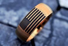 a wooden ring with an american flag painted on the front and side, sitting on a stone surface