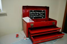 a red tool box sitting on top of a table next to a chalkboard sign