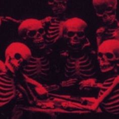 a group of skeletons sitting next to each other in front of a red lit room