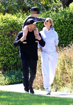 a man and woman walking down a sidewalk with one holding the other's head