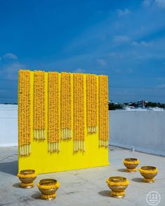 four yellow vases sitting in front of a wall with flowers on it