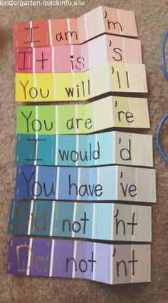 rainbow cards with words written on them sitting on the floor next to scissors and yarn