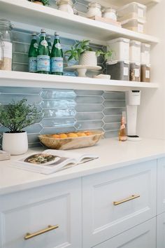 a kitchen with white cupboards and shelves filled with bottles, dishes, and other items