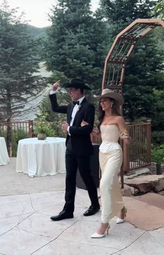 a man in a suit and tie standing next to a woman wearing a white dress