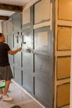 a man is painting the side of a garage door with paint rollers on it